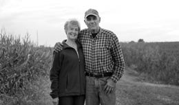 Middle-aged couple posing together in a field.